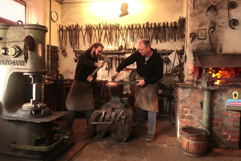 Herr Koch und sein Geselle beim herstellen handgefertigter Metallarbeiten